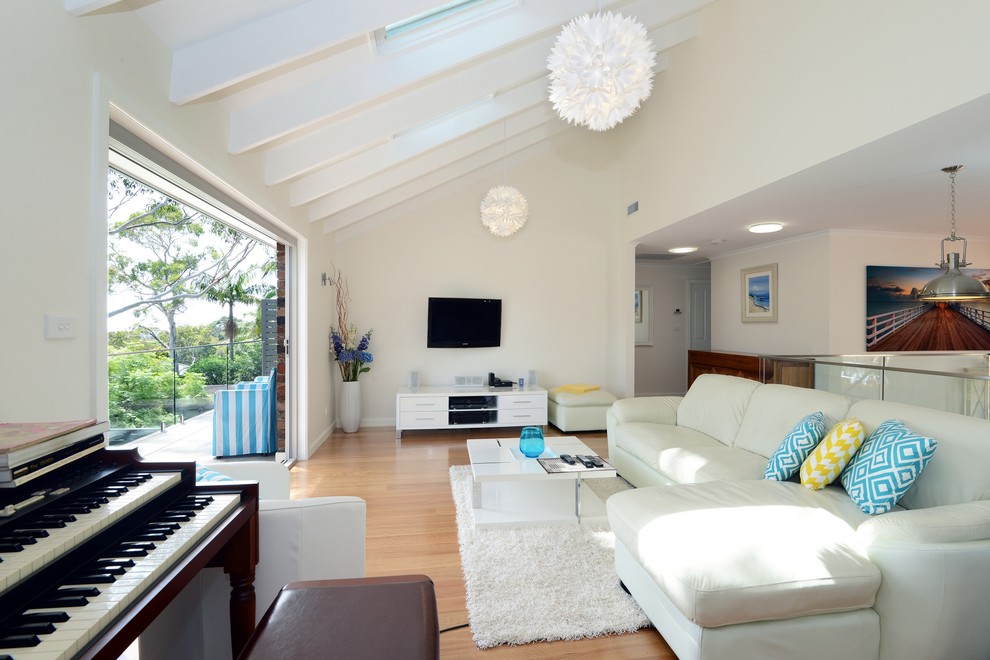 Modelo de sala de estar abierta actual de tamaño medio con paredes blancas, suelo de baldosas de porcelana y televisor colgado en la pared