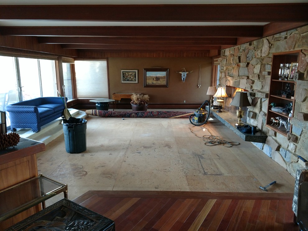 Imagen de sala de estar cerrada retro de tamaño medio con paredes marrones, suelo de madera en tonos medios, todas las chimeneas, marco de chimenea de piedra y suelo marrón