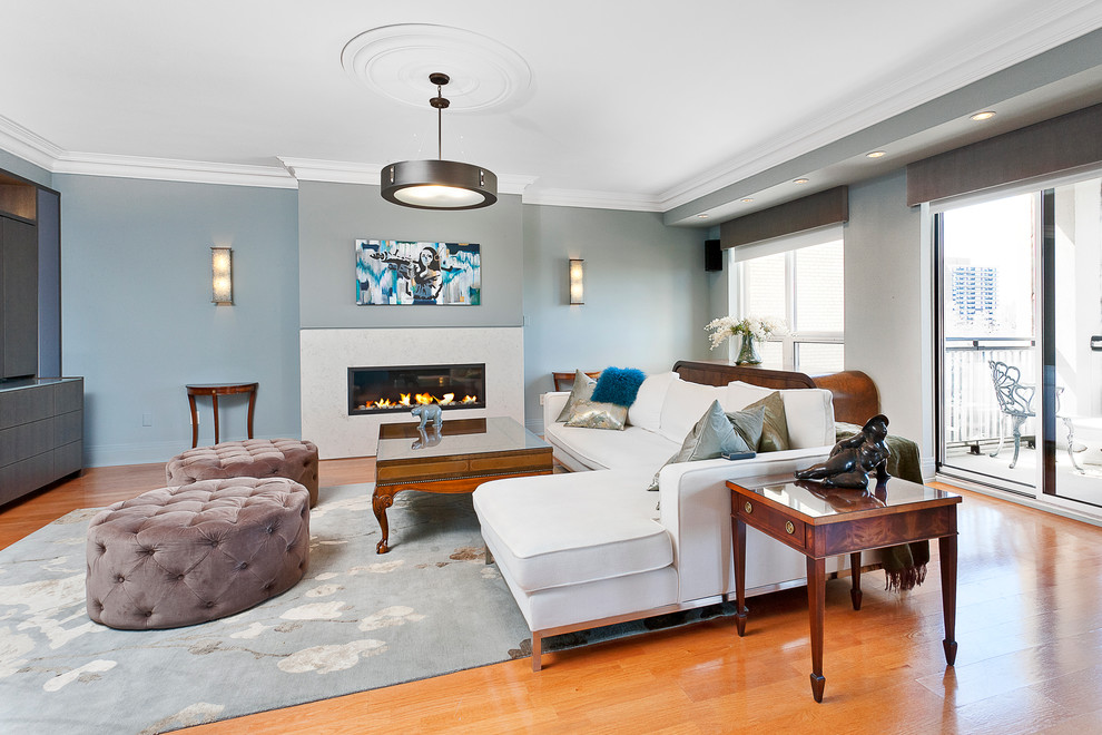 Exemple d'une salle de séjour chic ouverte avec un mur bleu, un sol en bois brun, une cheminée ribbon et un manteau de cheminée en pierre.