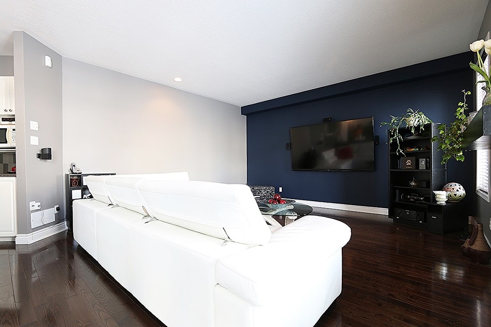 Inredning av ett modernt mellanstort avskilt allrum, med blå väggar, mörkt trägolv, en väggmonterad TV och en standard öppen spis