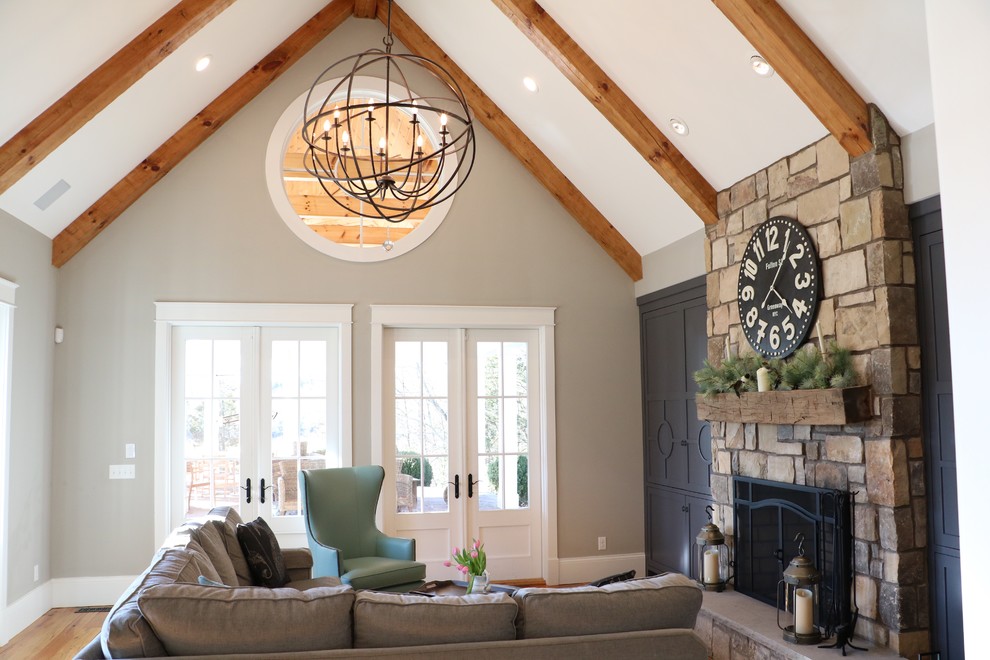 Large country enclosed medium tone wood floor family room photo in Other with gray walls, a standard fireplace, a stone fireplace and a media wall