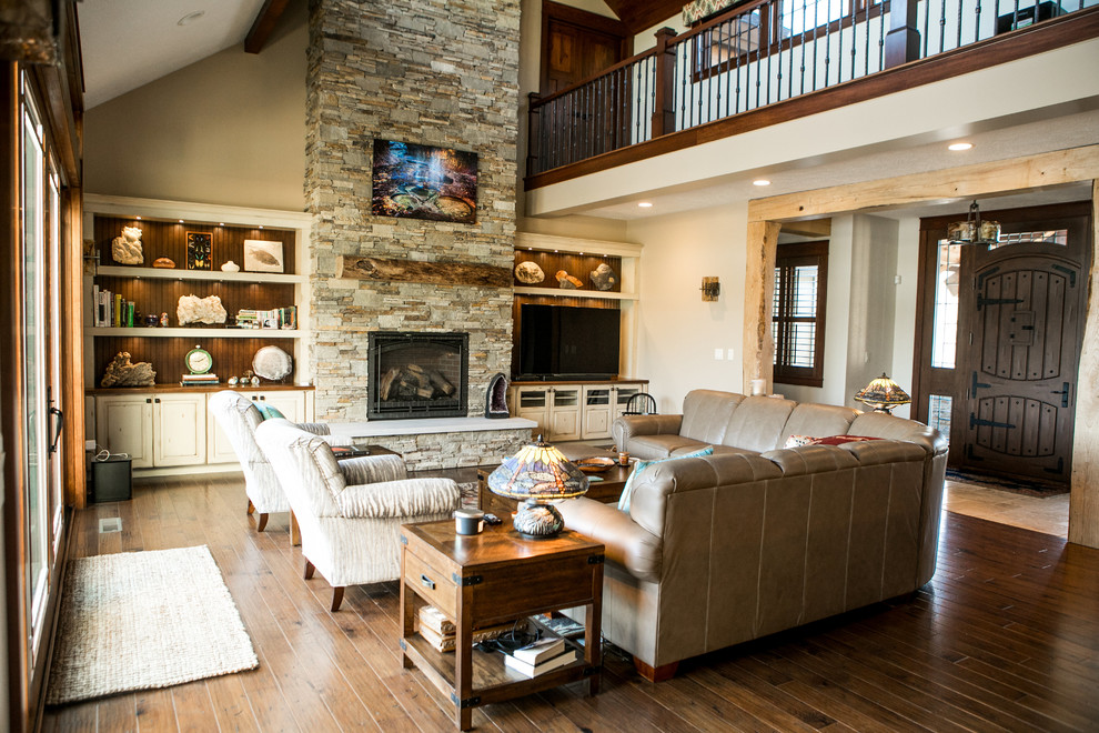 This is an example of a large open plan games room in Indianapolis with dark hardwood flooring and a stone fireplace surround.