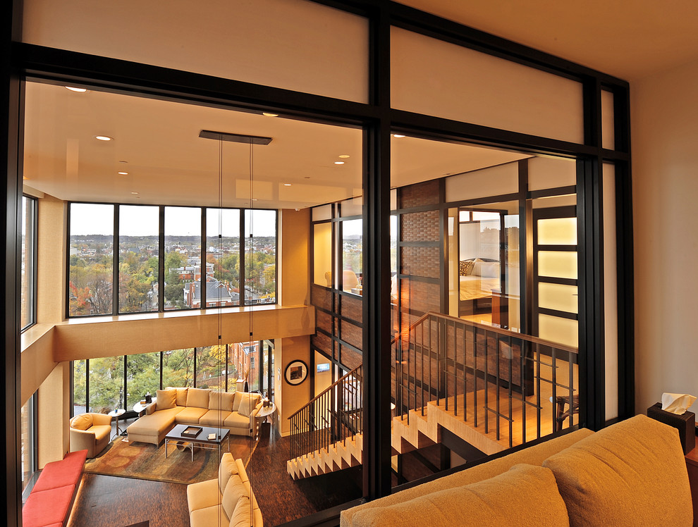 На фото: открытая гостиная комната среднего размера в современном стиле с бежевыми стенами, пробковым полом, скрытым телевизором и коричневым полом без камина
