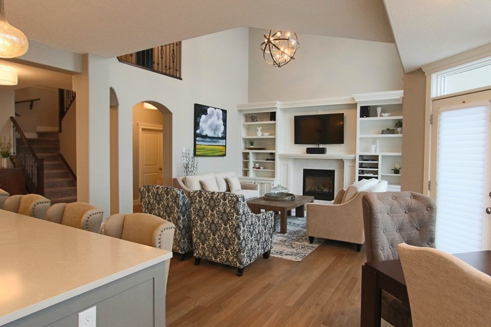 This is an example of a medium sized classic open plan games room in Calgary with grey walls, light hardwood flooring, a tiled fireplace surround and a wall mounted tv.