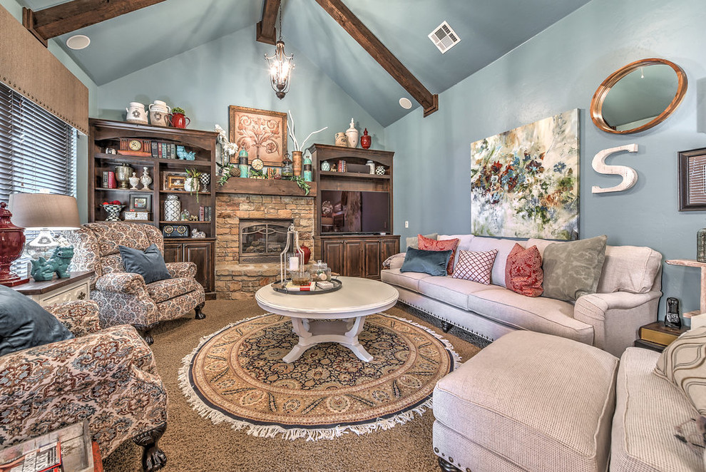 Cette image montre une salle de séjour style shabby chic de taille moyenne et ouverte avec un mur bleu, moquette, une cheminée standard, un manteau de cheminée en pierre, un téléviseur fixé au mur et un sol beige.