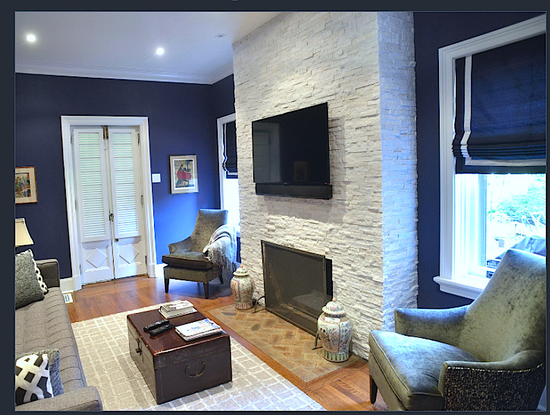 Foto de sala de estar bohemia con paredes azules, suelo de madera en tonos medios, marco de chimenea de piedra, televisor colgado en la pared, suelo marrón y todas las chimeneas