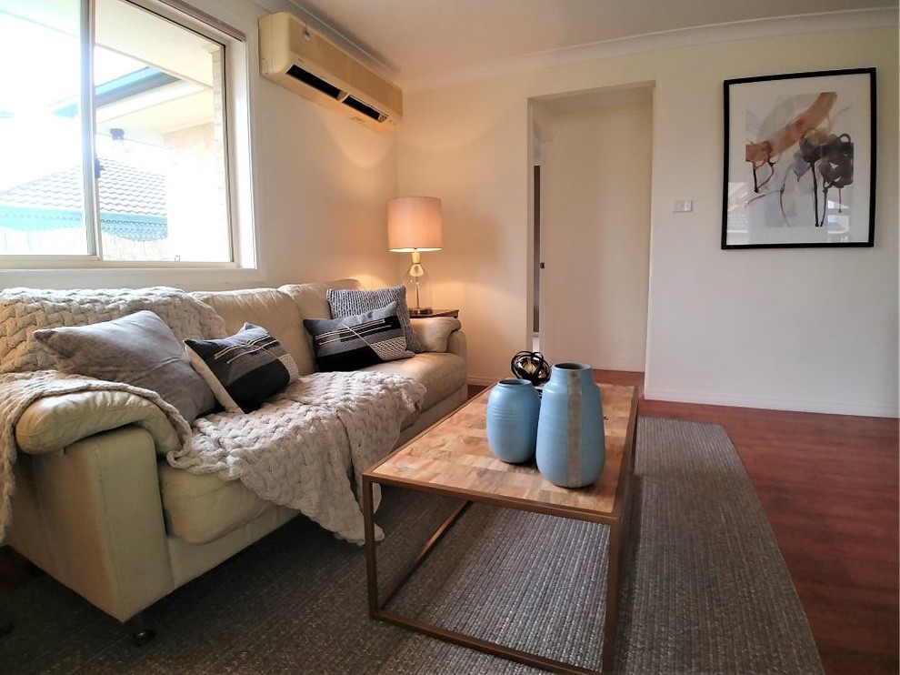 Ispirazione per un soggiorno minimal di medie dimensioni con pareti beige, pavimento in laminato e pavimento marrone