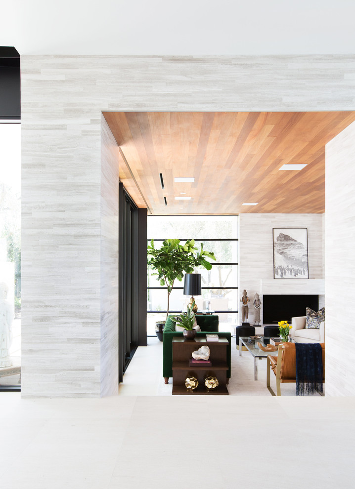Mittelgroßes, Abgetrenntes Modernes Wohnzimmer mit Hausbar, weißer Wandfarbe, Kalkstein, Eckkamin, gefliester Kaminumrandung und TV-Wand in Los Angeles