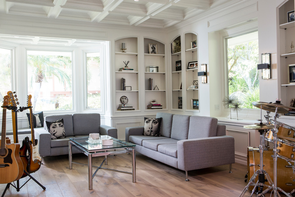 Imagen de sala de estar con rincón musical costera grande sin chimenea y televisor con paredes blancas y suelo de madera clara