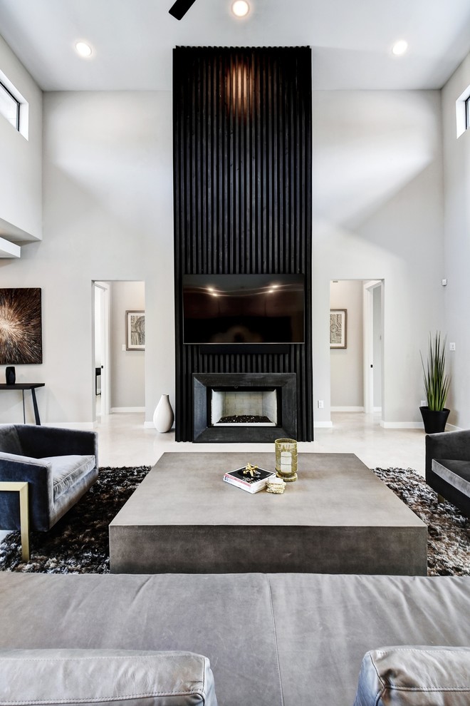 На фото: открытая гостиная комната среднего размера в современном стиле с серыми стенами, бетонным полом, стандартным камином, фасадом камина из дерева, телевизором на стене и серым полом с