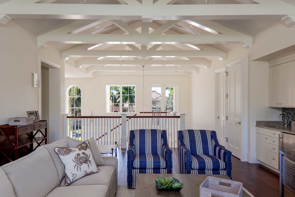 Imagen de sala de estar tipo loft tropical sin chimenea con paredes blancas y suelo de madera oscura