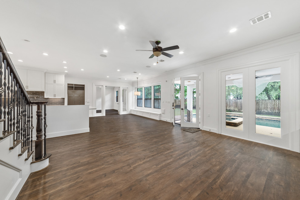 This is an example of a large classic open plan games room in Houston with a reading nook, white walls, laminate floors, a standard fireplace, a stone fireplace surround, no tv and brown floors.