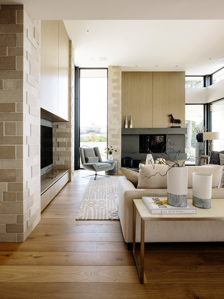 Ejemplo de sala de estar abierta contemporánea grande con suelo de madera en tonos medios, todas las chimeneas, marco de chimenea de piedra, televisor colgado en la pared, paredes blancas y suelo marrón