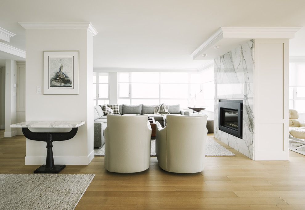 Источник вдохновения для домашнего уюта: открытая гостиная комната среднего размера в стиле неоклассика (современная классика) с белыми стенами, светлым паркетным полом, стандартным камином и фасадом камина из камня
