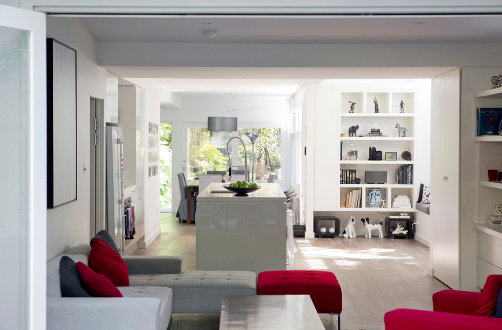 Пример оригинального дизайна: открытая гостиная комната среднего размера в современном стиле с белыми стенами, светлым паркетным полом, скрытым телевизором и коричневым полом