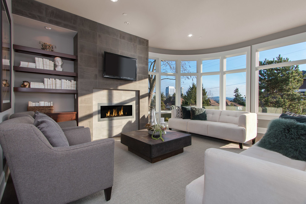 Imagen de sala de estar contemporánea con paredes grises, suelo de madera oscura, chimenea lineal, marco de chimenea de piedra, televisor colgado en la pared y suelo marrón