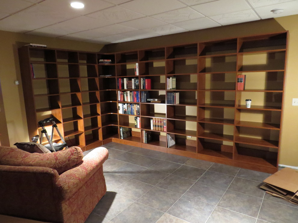 Foto de sala de estar con biblioteca abierta contemporánea grande sin chimenea y televisor con paredes marrones, suelo de pizarra y marco de chimenea de baldosas y/o azulejos