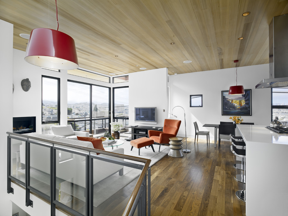 Immagine di un soggiorno design stile loft con pareti bianche, pavimento in legno massello medio, TV a parete e tappeto