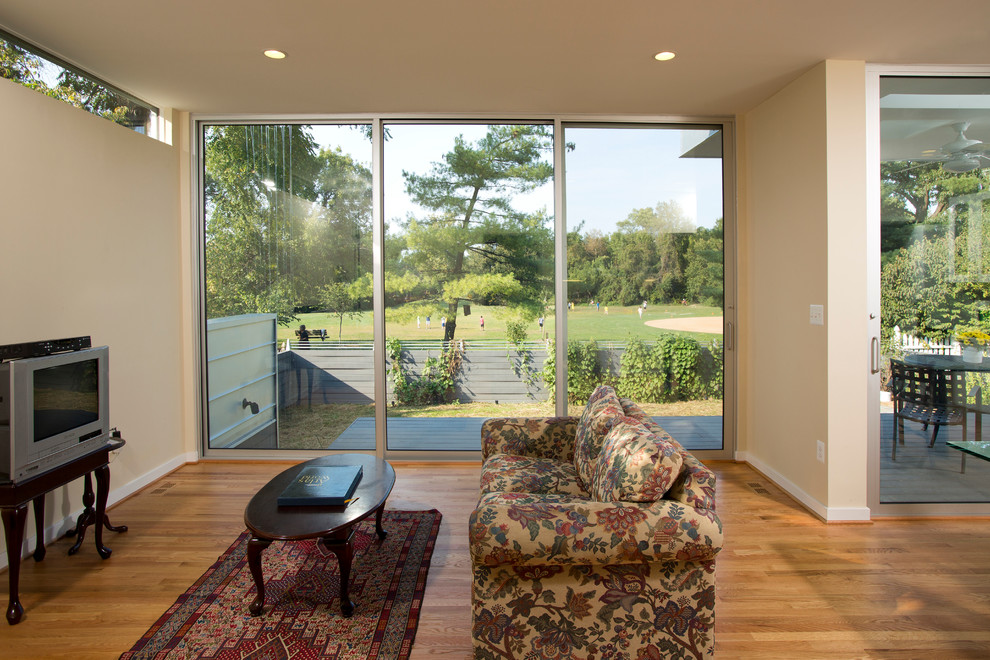 Esempio di un soggiorno design aperto e di medie dimensioni con pareti beige, parquet chiaro e TV autoportante