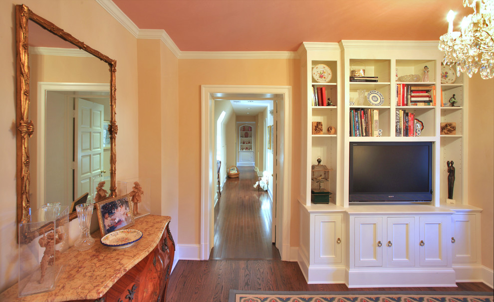 Ejemplo de sala de estar con biblioteca cerrada clásica de tamaño medio con paredes rosas, suelo de madera oscura y pared multimedia