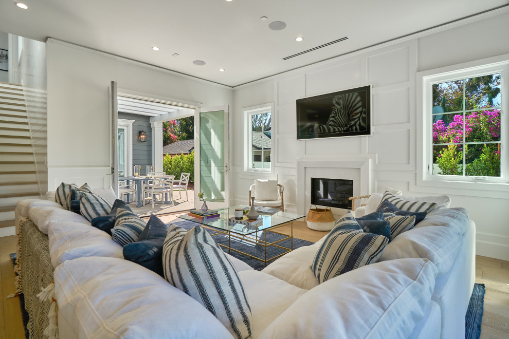 Idee per un soggiorno minimal aperto con pareti bianche, parquet chiaro, camino classico, TV a parete, pavimento beige e pannellatura