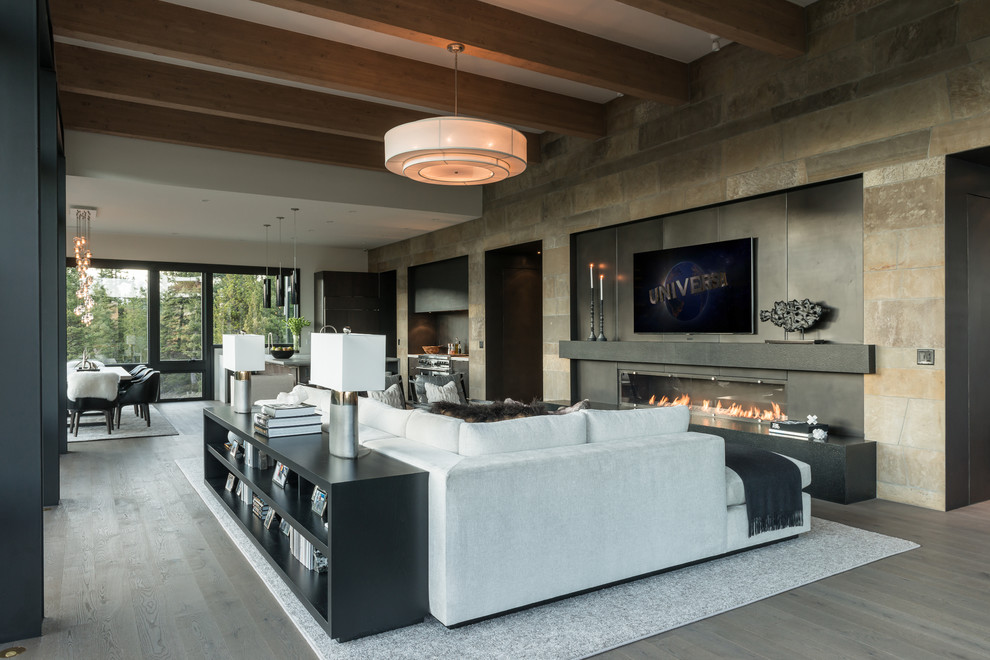 Photo of a large contemporary open plan games room in Other with beige walls, medium hardwood flooring, a ribbon fireplace, a metal fireplace surround, a wall mounted tv and brown floors.