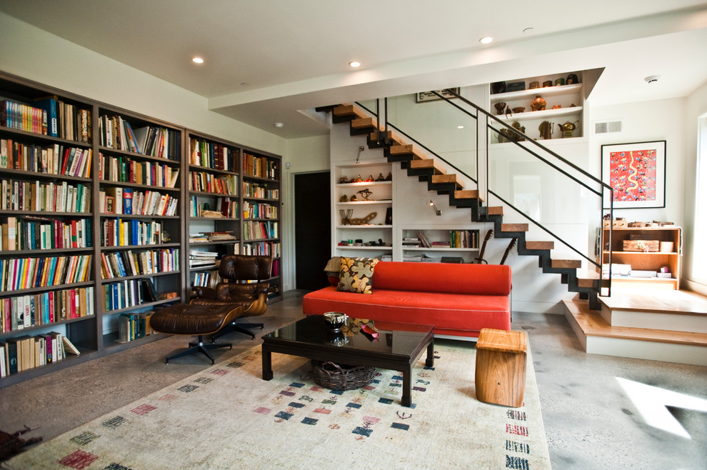 Foto de sala de estar con biblioteca cerrada contemporánea con paredes blancas, suelo de cemento, suelo gris y alfombra