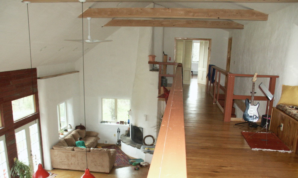 Foto di un soggiorno di medie dimensioni e stile loft con pareti bianche, pavimento in legno massello medio, camino ad angolo e cornice del camino in intonaco