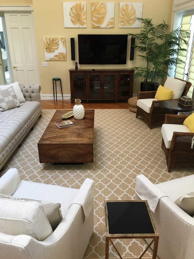 Modelo de sala de estar abierta clásica renovada grande sin chimenea con paredes beige, suelo de madera en tonos medios, televisor colgado en la pared y suelo marrón