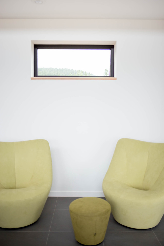 Modelo de sala de estar abierta moderna grande sin televisor con paredes blancas, suelo de pizarra y marco de chimenea de metal