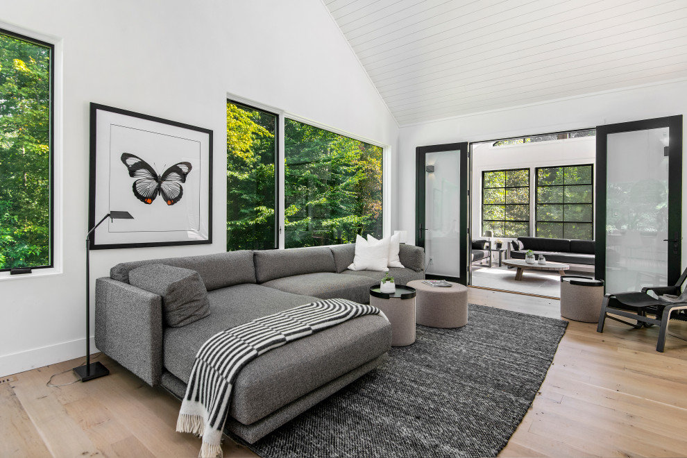 Imagen de sala de estar abierta minimalista con paredes blancas, suelo de madera clara y suelo beige