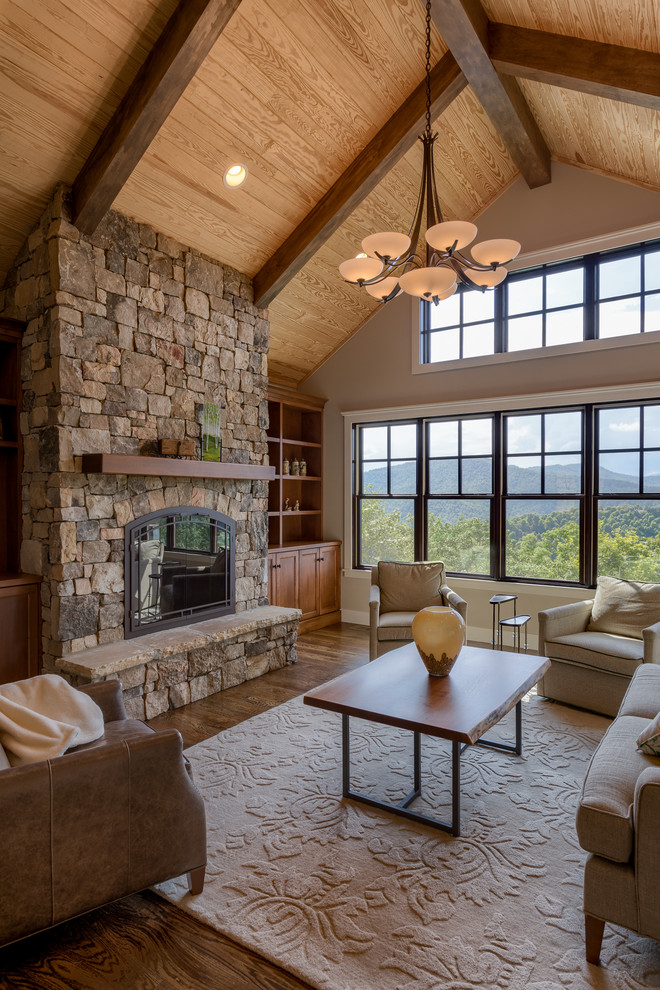 Foto de sala de estar de estilo americano grande sin televisor con paredes grises, suelo de madera en tonos medios, todas las chimeneas y marco de chimenea de piedra