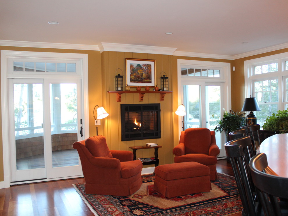 Idée de décoration pour une grande salle de séjour tradition avec un mur jaune, un sol en bois brun, une cheminée standard et un manteau de cheminée en bois.