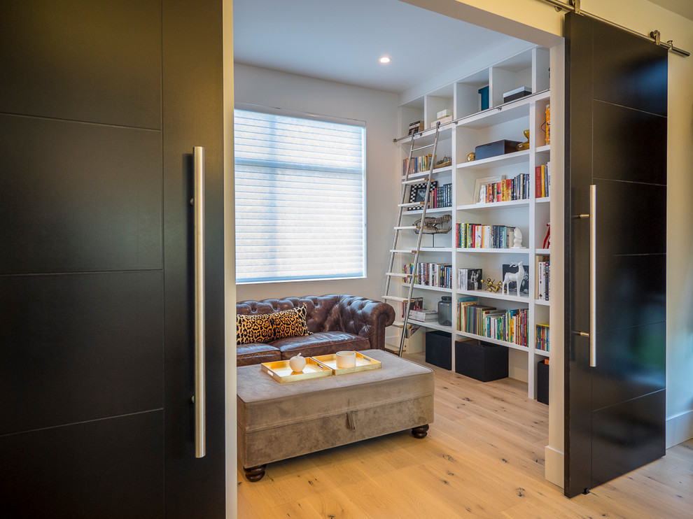 На фото: изолированная гостиная комната среднего размера в современном стиле с с книжными шкафами и полками, белыми стенами и светлым паркетным полом без телевизора