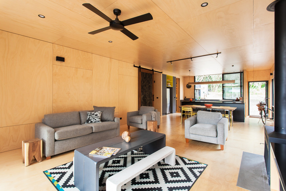 Imagen de sala de estar abierta contemporánea con paredes beige, suelo de contrachapado y estufa de leña