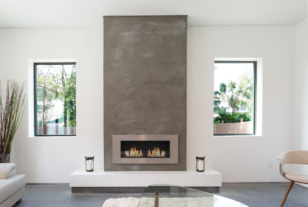 This is an example of a large modern games room in Tampa with white walls, concrete flooring, a ribbon fireplace, a concrete fireplace surround and a wall mounted tv.