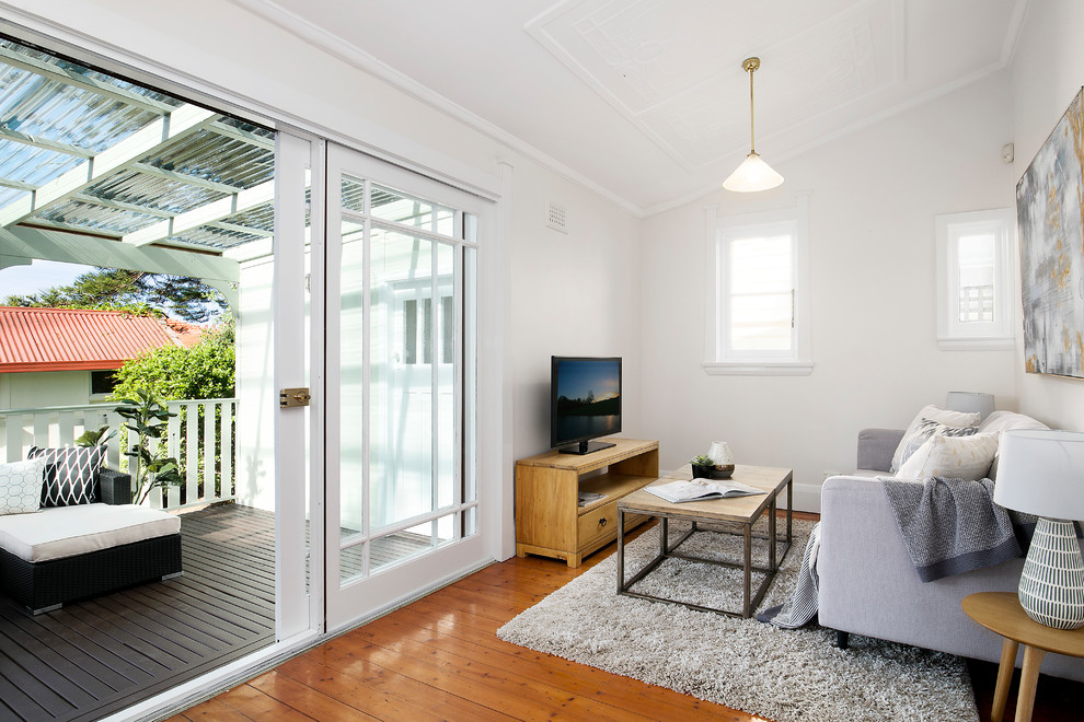 シドニーにあるミッドセンチュリースタイルのおしゃれなファミリールーム (白い壁、無垢フローリング、暖炉なし、据え置き型テレビ、茶色い床) の写真