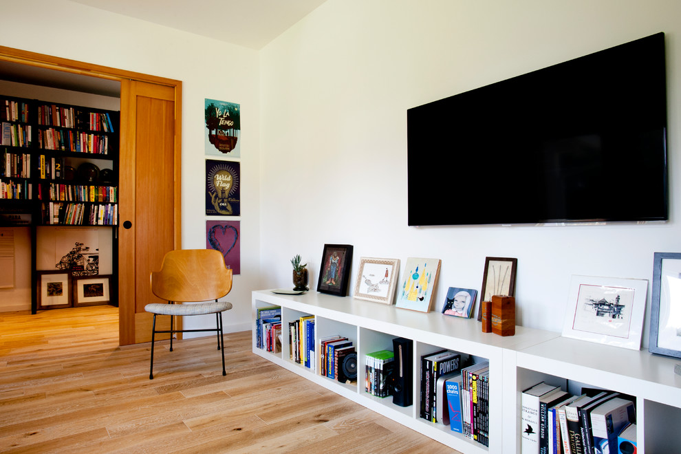 Inspiration pour une salle de séjour design de taille moyenne et fermée avec une bibliothèque ou un coin lecture, un mur blanc et un téléviseur fixé au mur.