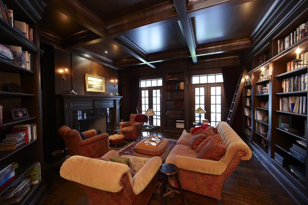 Modelo de sala de estar con biblioteca cerrada clásica de tamaño medio sin televisor con paredes marrones, suelo de madera oscura, todas las chimeneas y marco de chimenea de piedra