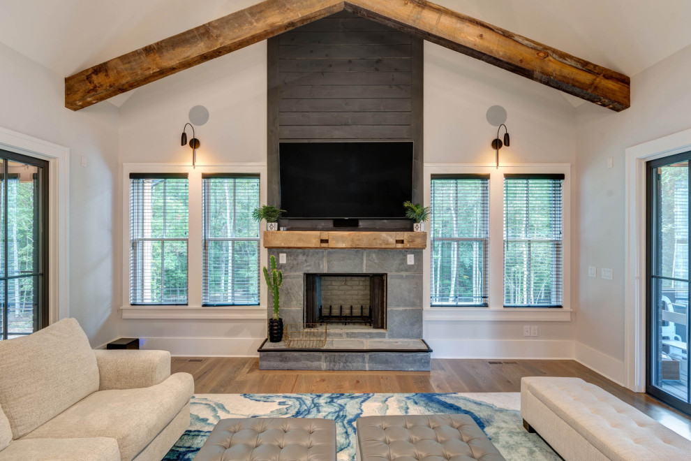 This is an example of a large modern open plan games room in Atlanta with grey walls, medium hardwood flooring, a standard fireplace, a timber clad chimney breast, a wall mounted tv, brown floors, exposed beams and tongue and groove walls.