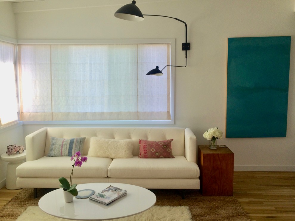Idéer för ett litet minimalistiskt allrum med öppen planlösning, med vita väggar, ljust trägolv och en väggmonterad TV