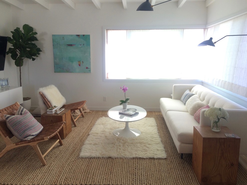 Modelo de sala de estar abierta nórdica pequeña sin chimenea con paredes blancas, suelo de madera clara y televisor colgado en la pared