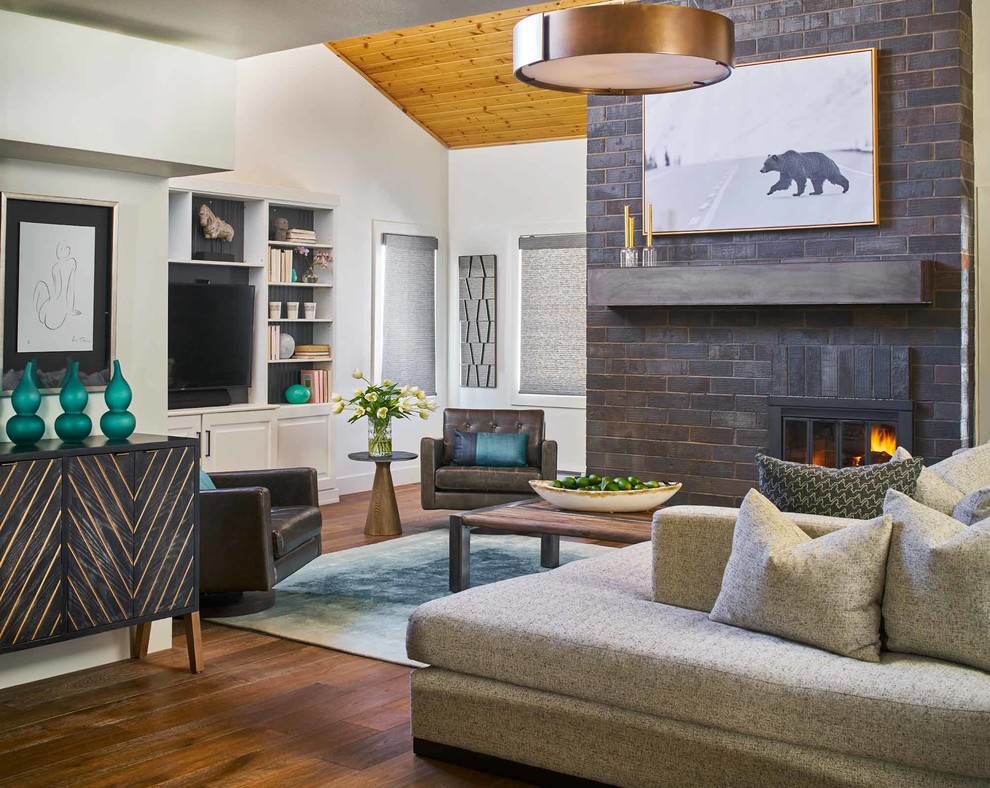 Imagen de sala de estar abierta contemporánea con paredes blancas, suelo de madera en tonos medios, todas las chimeneas, marco de chimenea de ladrillo, pared multimedia y alfombra