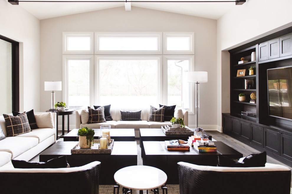 Modelo de sala de estar abierta y abovedada mediterránea grande con paredes blancas, suelo de madera en tonos medios, pared multimedia y suelo marrón