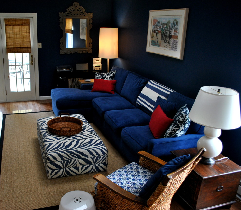 Foto de sala de estar con biblioteca tipo loft ecléctica grande sin chimenea con paredes azules, suelo de madera en tonos medios y televisor retractable