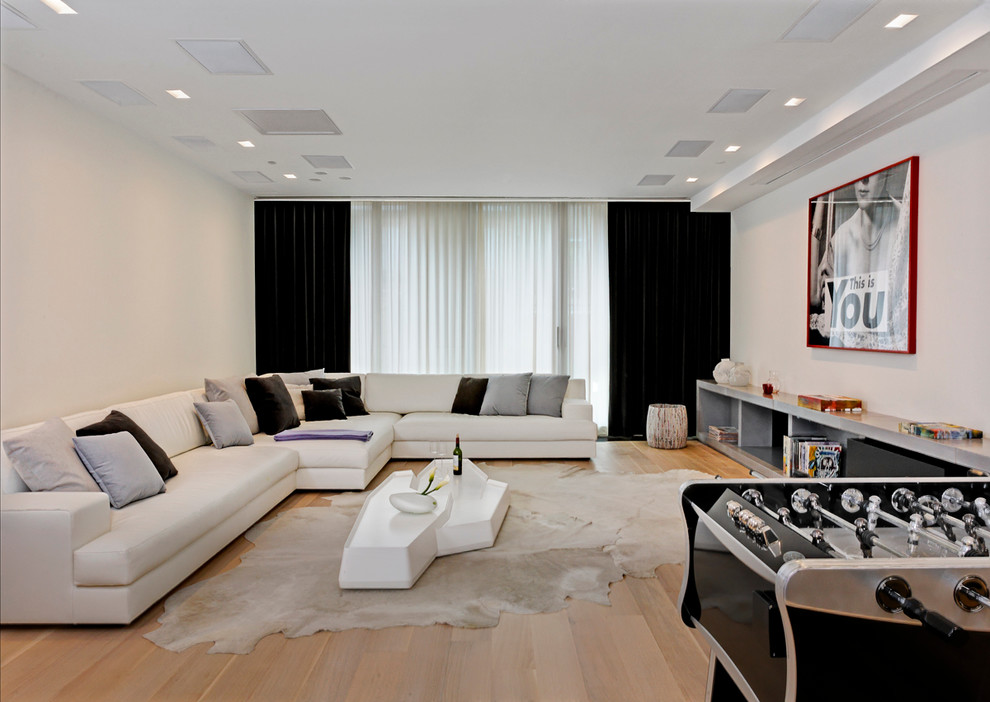 Réalisation d'une salle de séjour design ouverte avec salle de jeu, un mur blanc et un sol en bois brun.