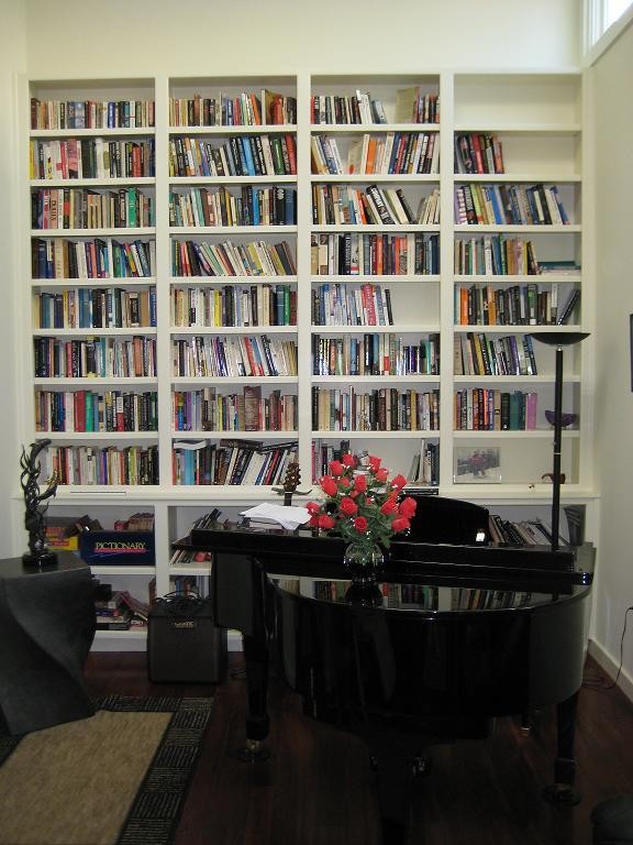 Cette image montre une salle de séjour bohème de taille moyenne et fermée avec une bibliothèque ou un coin lecture, un mur blanc, parquet foncé et un sol marron.