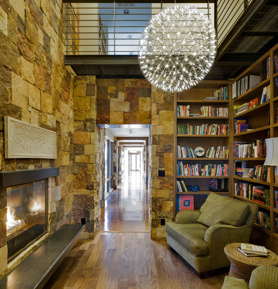 Immagine di un ampio soggiorno minimal con libreria, parquet scuro, cornice del camino in pietra, nessuna TV e camino classico