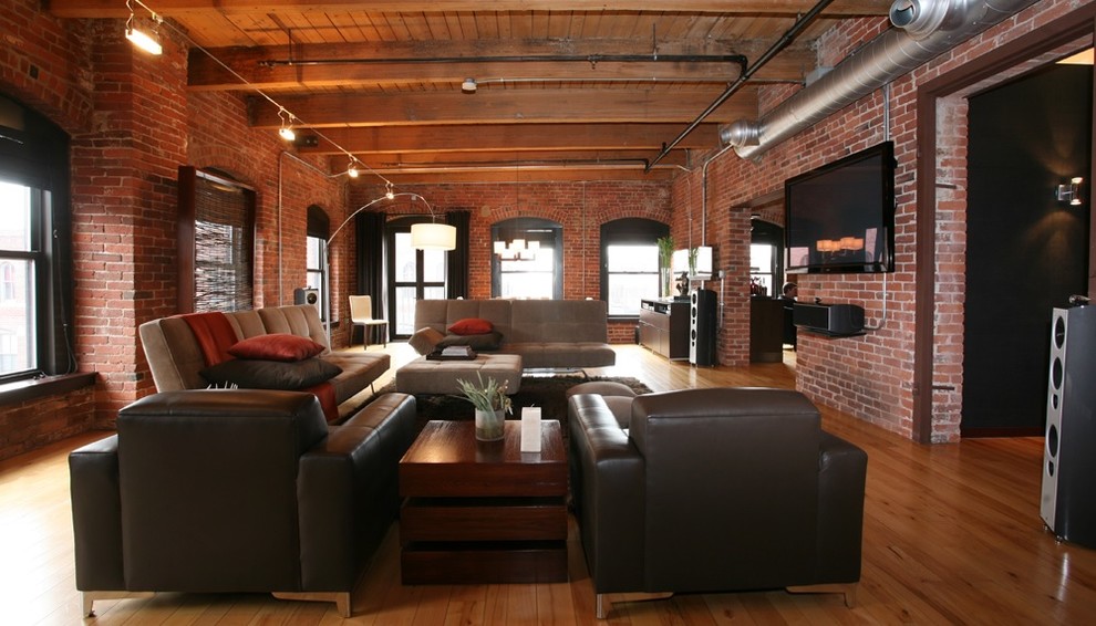 Foto de sala de estar abierta industrial con paredes rojas, suelo de madera en tonos medios y televisor colgado en la pared