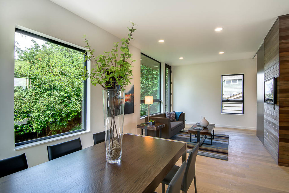 Diseño de sala de estar abierta minimalista de tamaño medio sin chimenea con paredes blancas, suelo de madera clara y televisor colgado en la pared